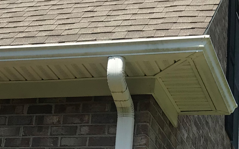 Photo of gutters and downspout at the corner of a brick house